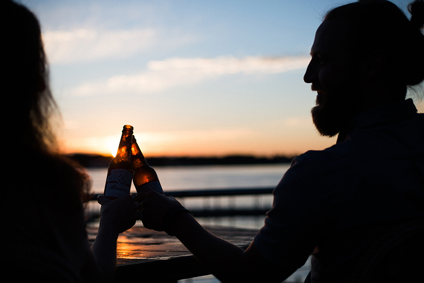 sunset couple cheers their drinks at mylestom cabins accommodation coffs harbour