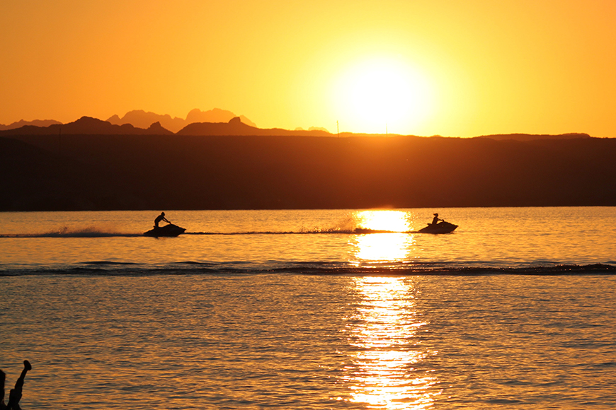 warm sunset glow over bellinger river and silhouette of two jetskis near mylestom cabins accommodation coffs harbour